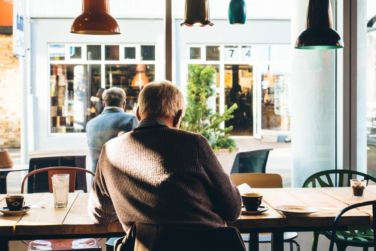 elderly man sitting at table in cafe