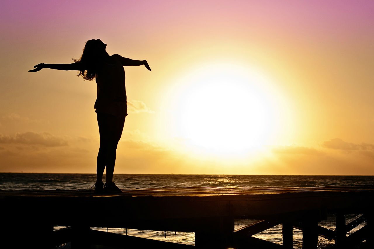 Woman facing sunset over water