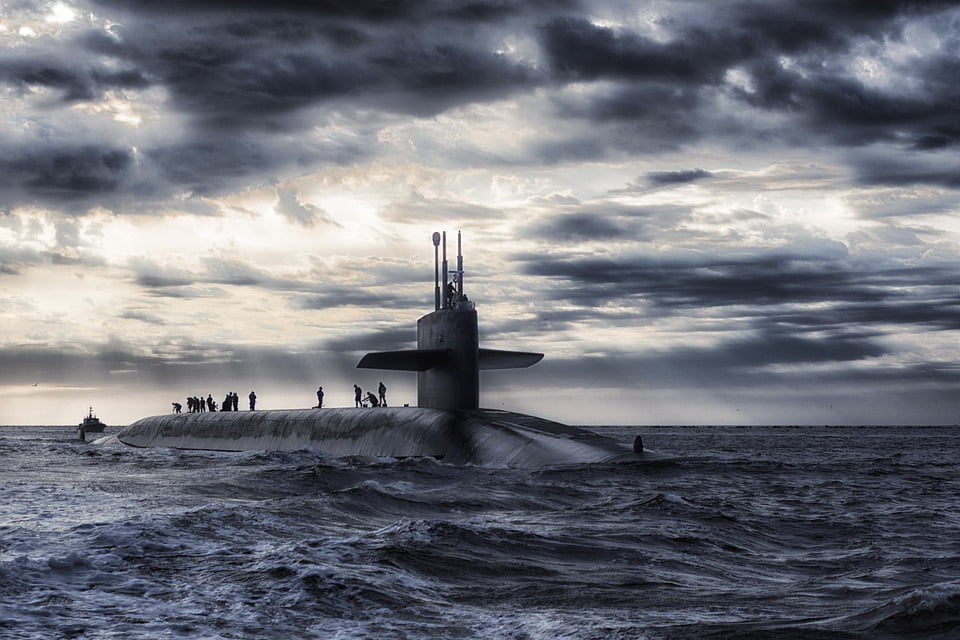 navy personnel on the top of a submarine at sea