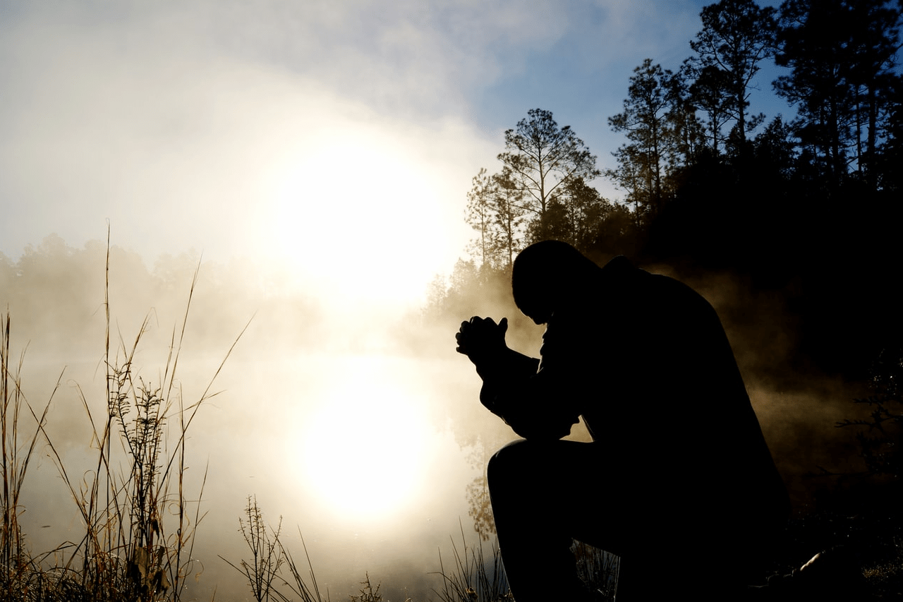 man praying by pond