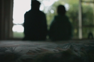 child and adult sitting on a bed